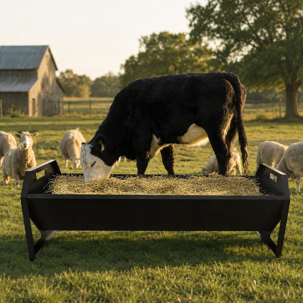 Mincy Pets 22-gallon black galvanized steel livestock hay feeder with a V-shaped trough in a sunny farm pasture.
