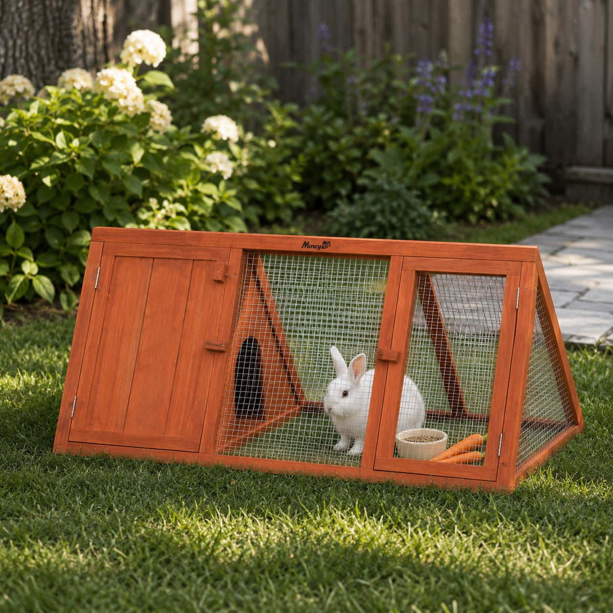 Mincy Pets orange wooden rabbit hutch with wire mesh run and a white bunny sitting inside on a grassy lawn.